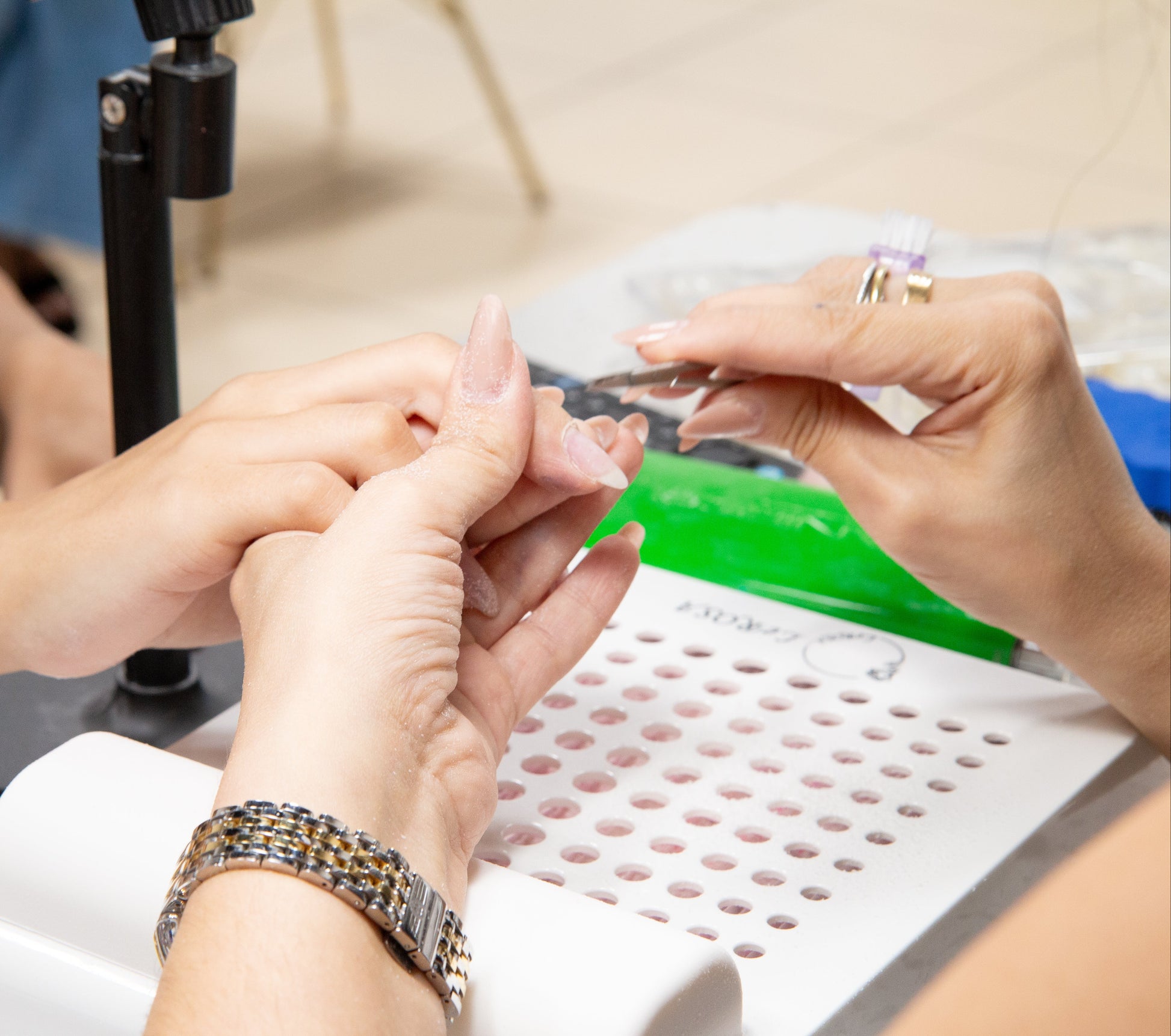 Woman working on nails for a client at Mai Phuong Academy